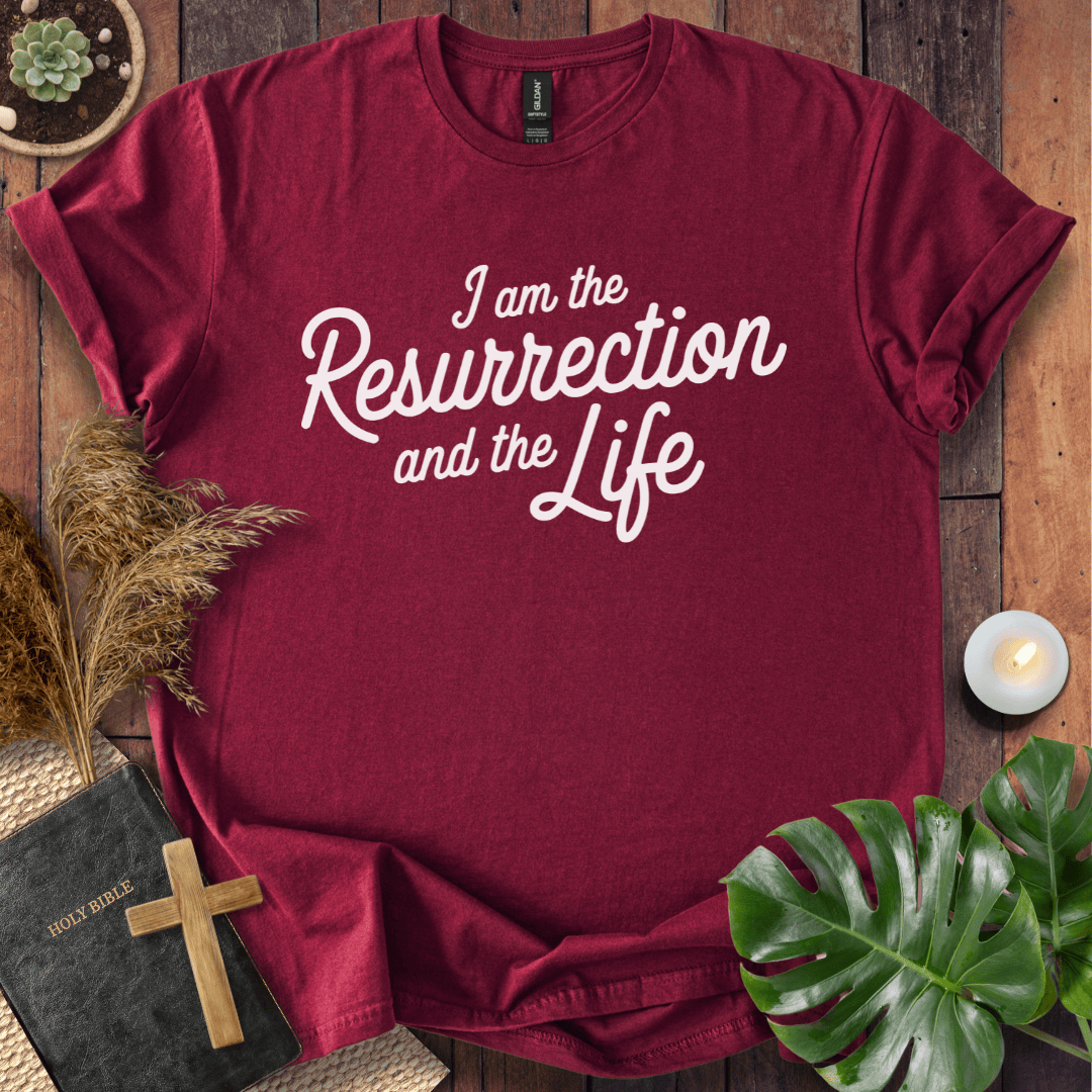Christian t shirt for women featuring white script 'I am the Resurrection and the Life' on a rustic wood table.