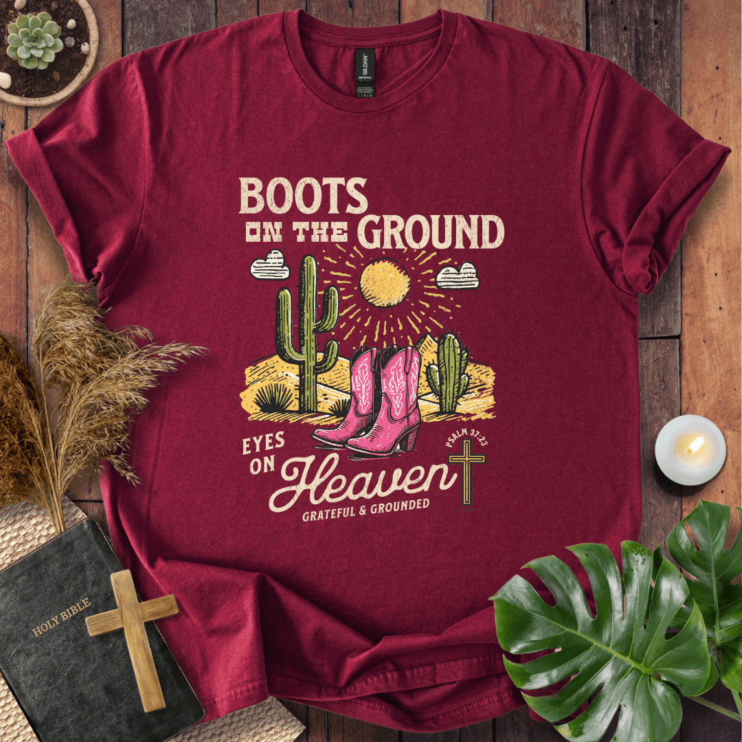 Christian t-shirt with pink cowboy boots, cacti, and "Boots on the Ground Eyes on Heaven" text for women's faith fashion.