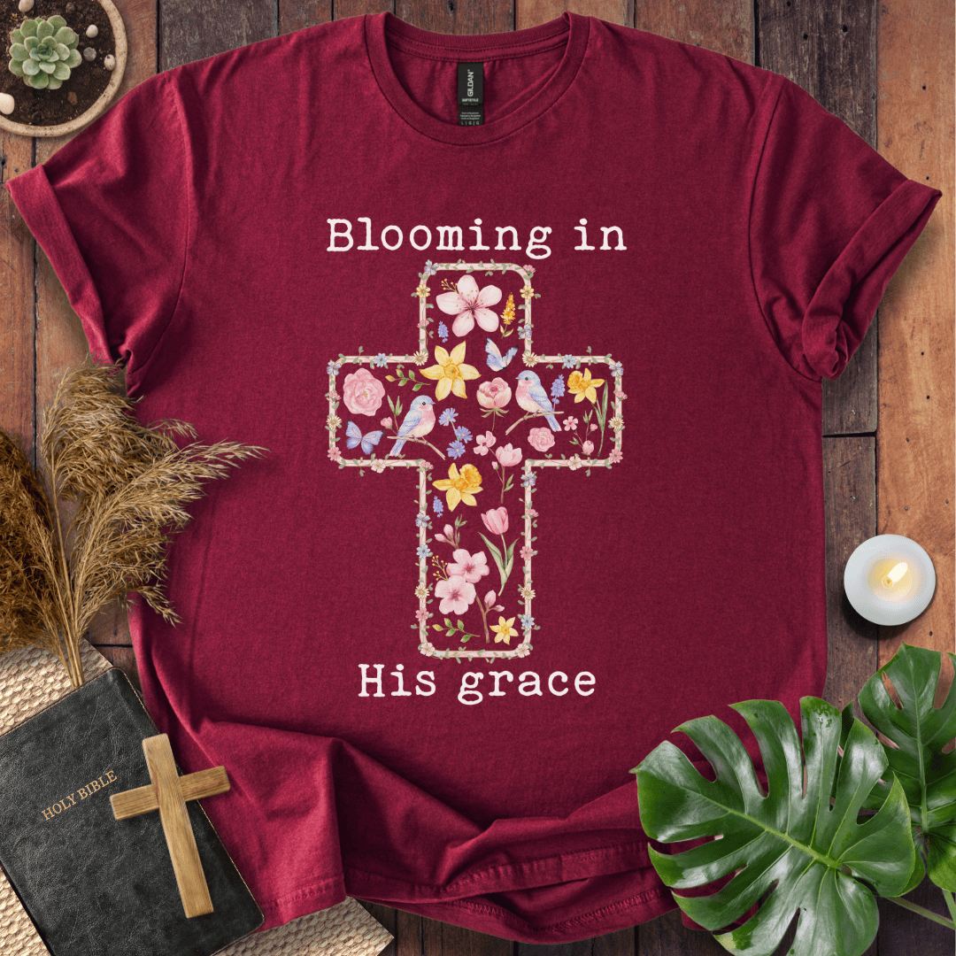 t-shirt featuring a cross filled with colorful wildflowers and birds, with the text "Blooming in His grace".