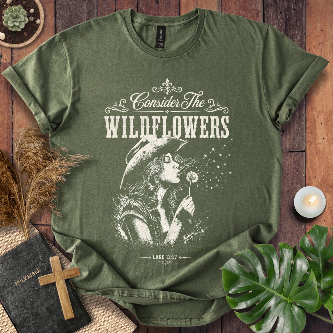 graphic tee reading Consider the Wildflowers Luke 12:27, featuring a woman in a cowboy hat blowing a dandelion.