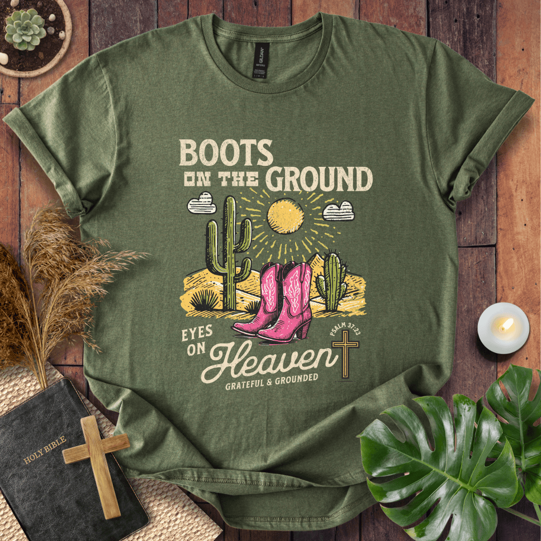 Christian t-shirt with pink cowboy boots, cacti, and "Boots on the Ground Eyes on Heaven" text for women's faith fashion.