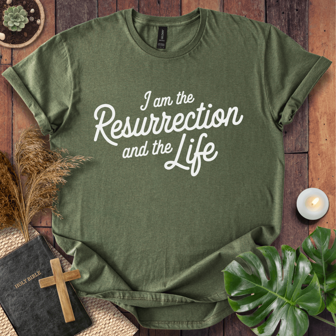 Christian t shirt for women featuring white script 'I am the Resurrection and the Life' on a rustic wood table.