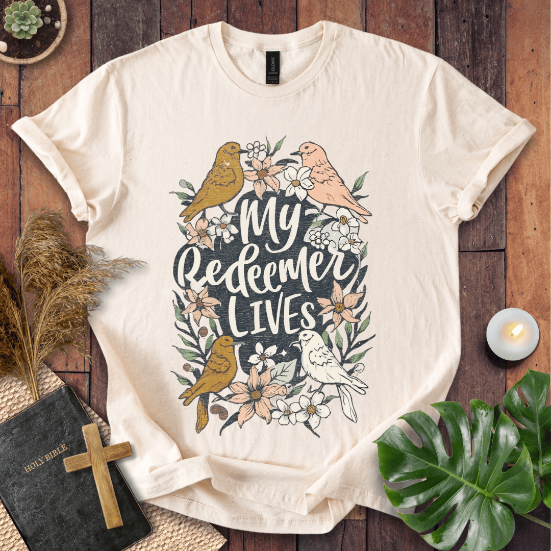 Christian Easter t-shirt with My Redeemer Lives text and birds on a wooden table next to a Holy Bible and a wooden cross.