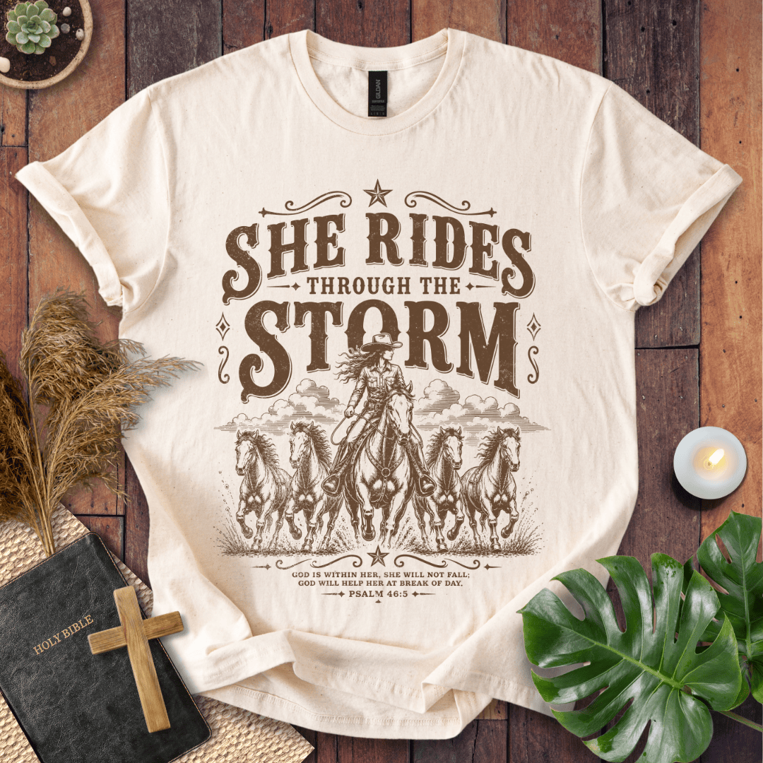 country t-shirt featuring a cowgirl riding a horse with the scripture text She Rides Through the Storm Psalm 46:5.
