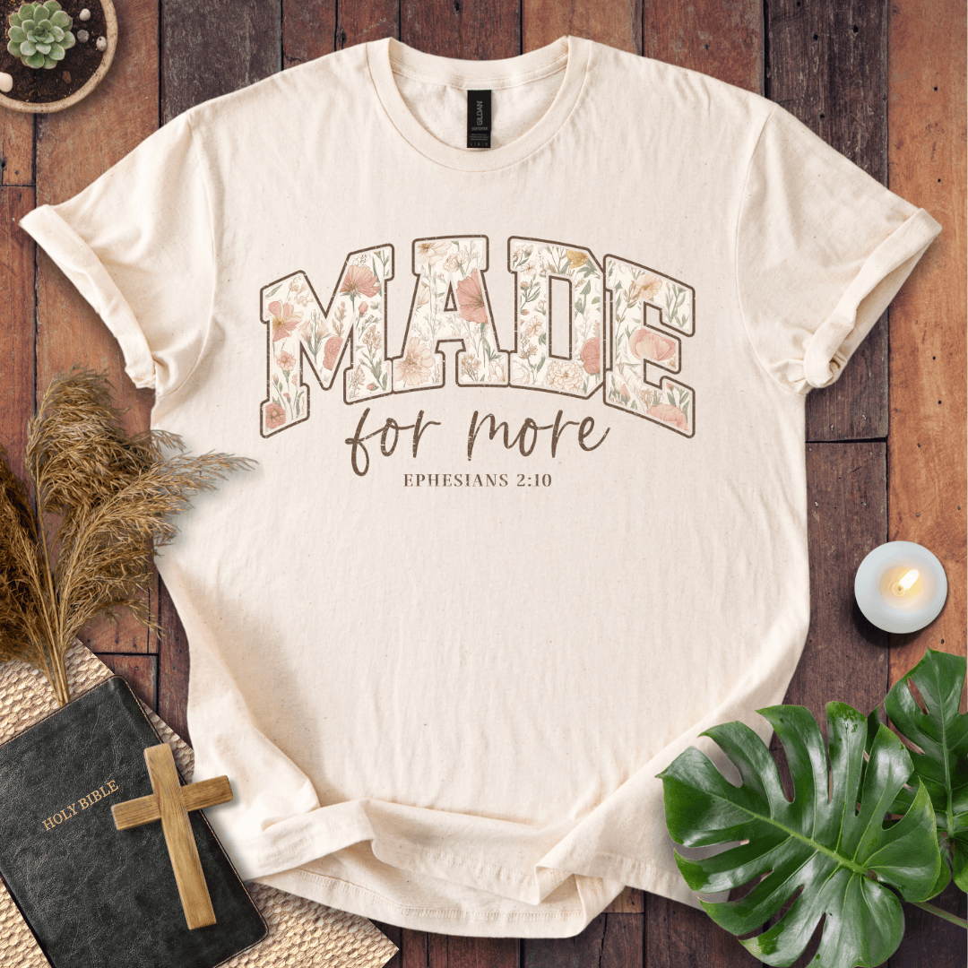 Beige t-shirt with 'Ride with Jesus, Let Him Lead the Way' text on a wooden surface with decorative items.