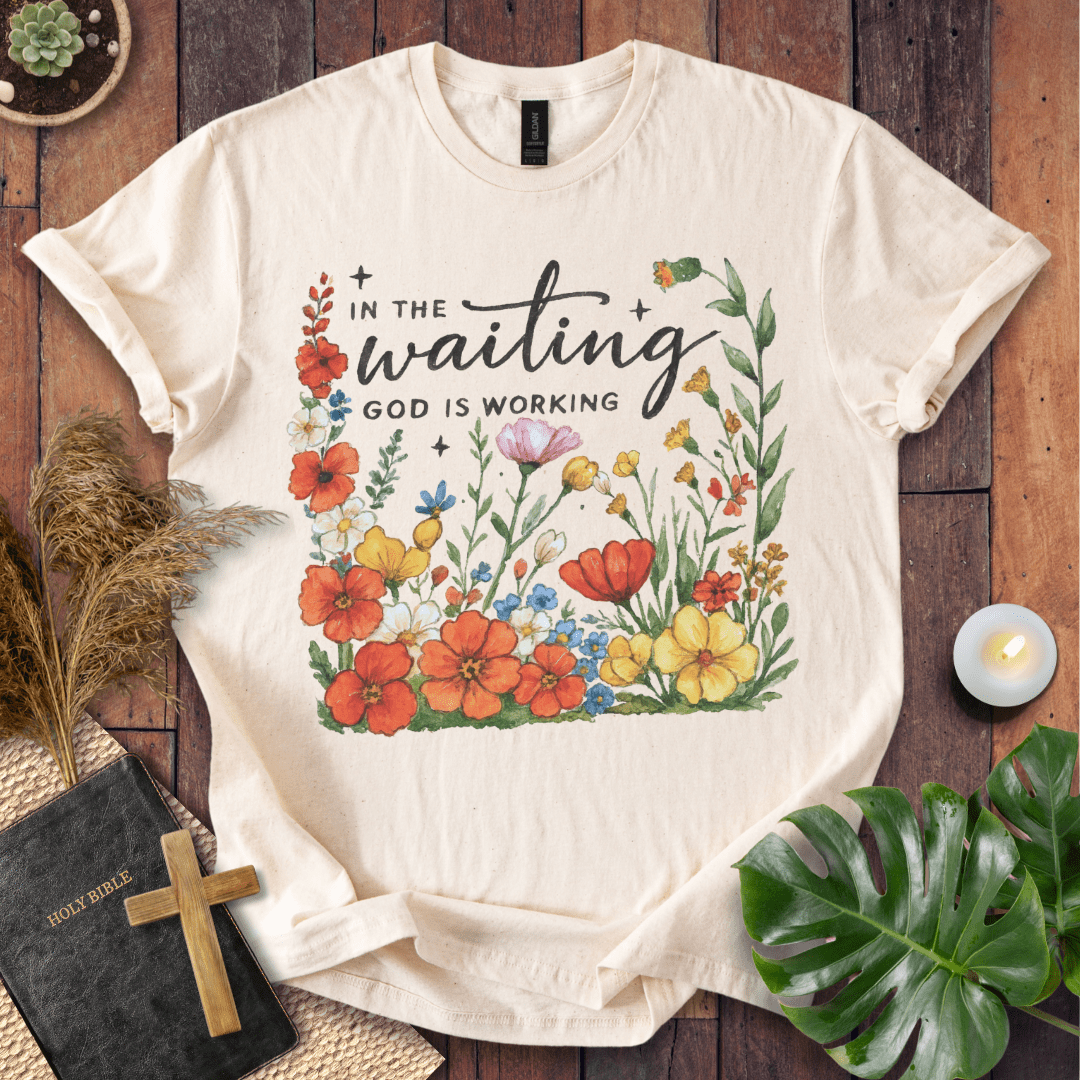 “In the Waiting God Is Working” Christian t-shirt with hand-lettered script and floral frame; encouragement faith tee.