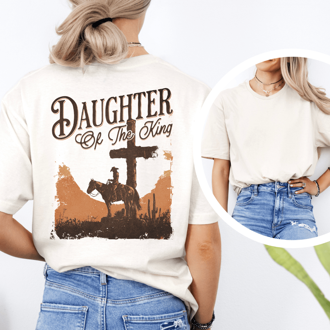 A woman wearing a graphic t-shirt with a western desert cross, cowboy on a horse, and Daughter of the King text.