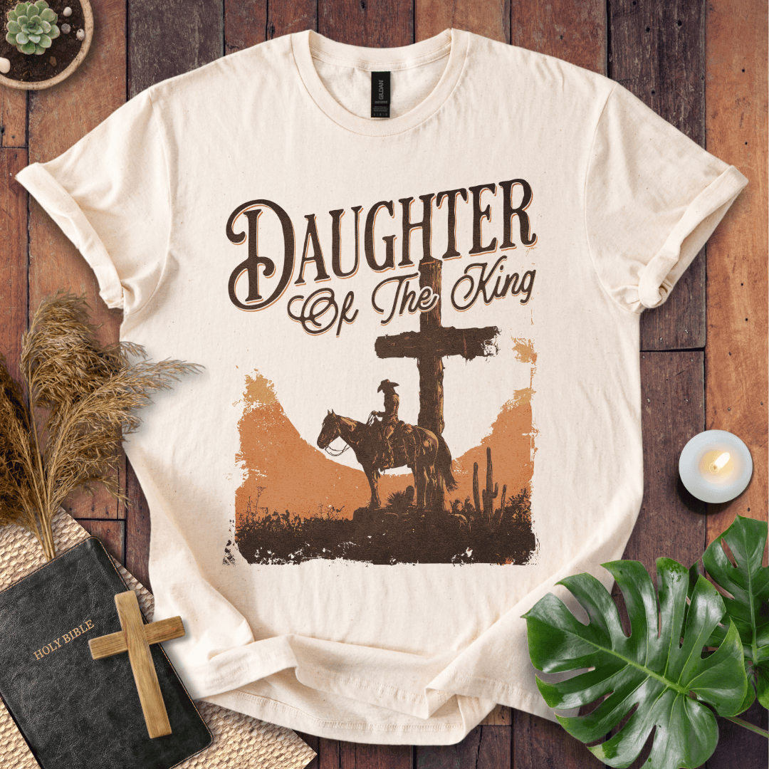 Western Christian t shirt for women featuring a rider on a horse by a cross in a desert sunset.