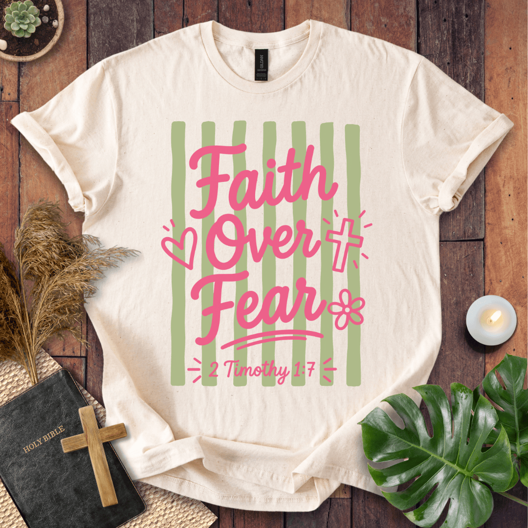 White t-shirt with religious design and text on a wooden surface with decor items.