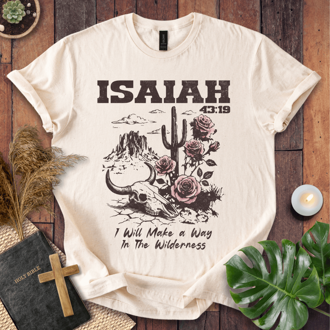 Beige t-shirt with 'ISAIAH 43:19' design on a wooden surface with plants and a Bible.