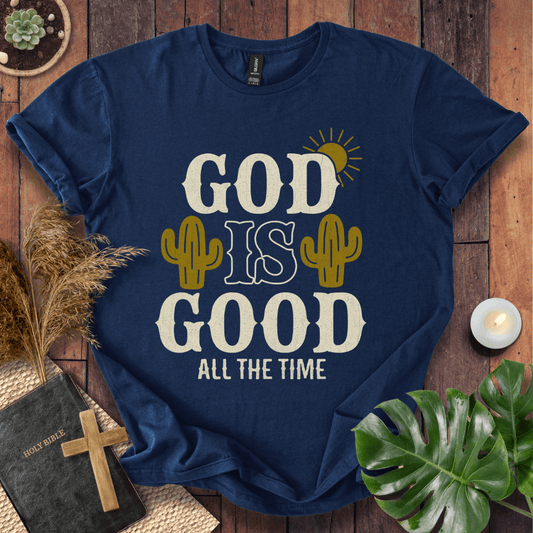 God Is Good All The Time t-shirt with cacti and sun graphics, styled with a Bible and wooden cross.