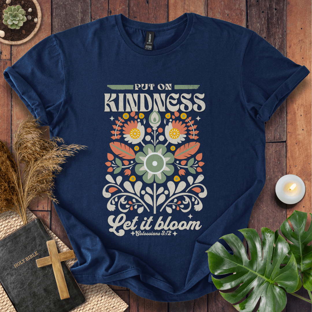“Put On Kindness — Let It Bloom” Colossians 3:12 retro floral Christian t-shirt in folk-art style.