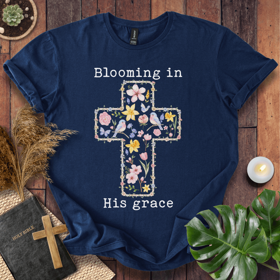t-shirt featuring a cross filled with colorful wildflowers and birds, with the text "Blooming in His grace".