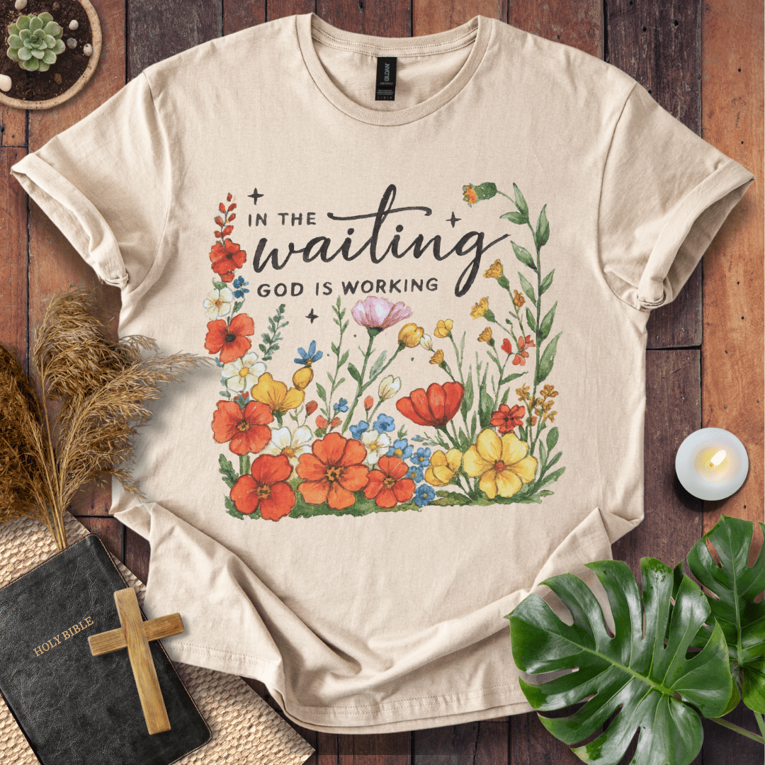 “In the Waiting God Is Working” Christian t-shirt with hand-lettered script and floral frame; encouragement faith tee.