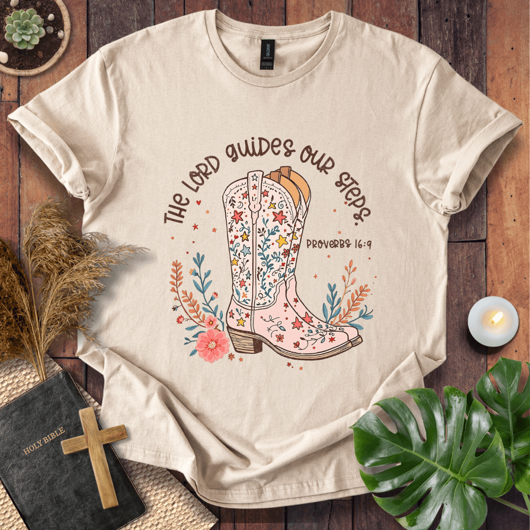 Christian t-shirt featuring a floral cowboy boot and the text The Lord Guides Our Steps Proverbs 16:9 in a rustic font.