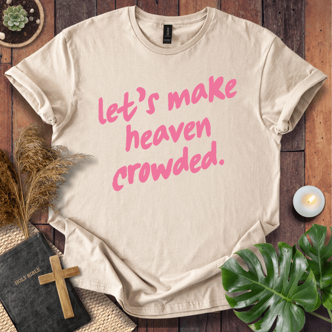 A beige graphic t-shirt with the phrase 'let's make heaven crowded.' printed in pink script across the front.