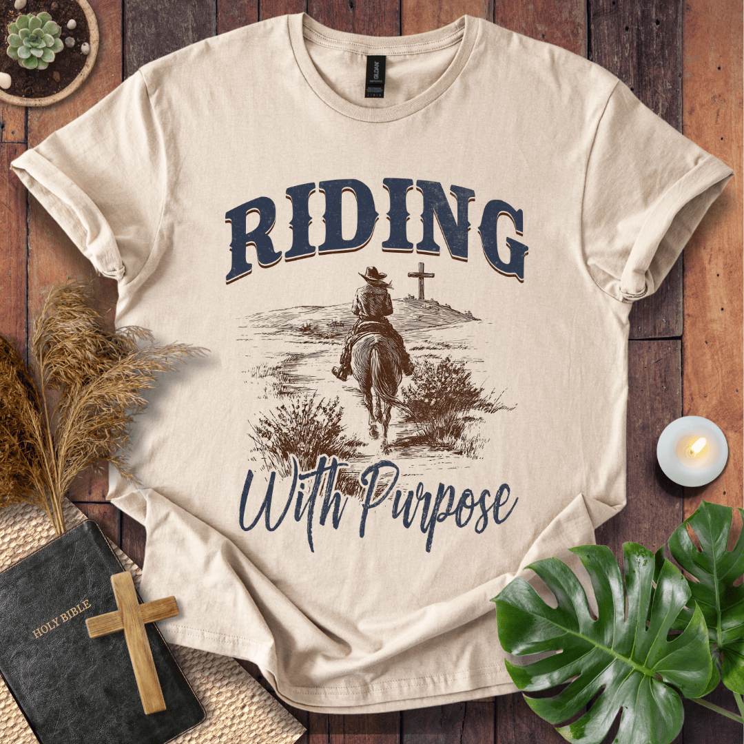 A lone rider on a horse approaching a cross on a Christian themed shirt with Riding With Purpose text.