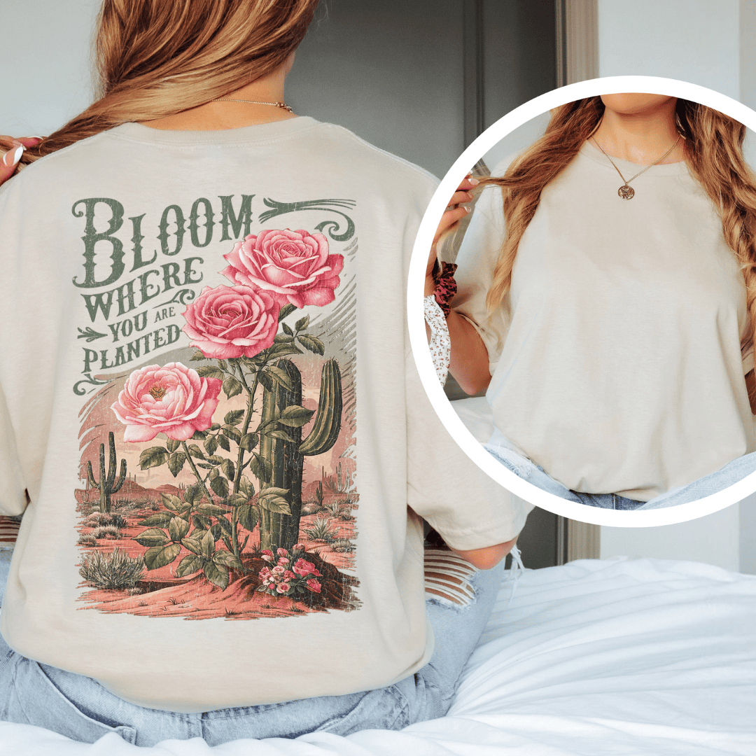 Back of a t-shirt featuring pink roses, green saguaro cacti, and text reading Bloom Where You Are Planted.