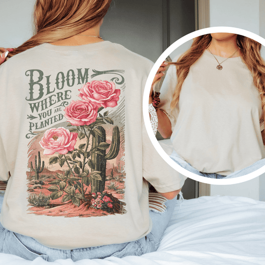 Back of a t-shirt featuring pink roses, green saguaro cacti, and text reading Bloom Where You Are Planted.