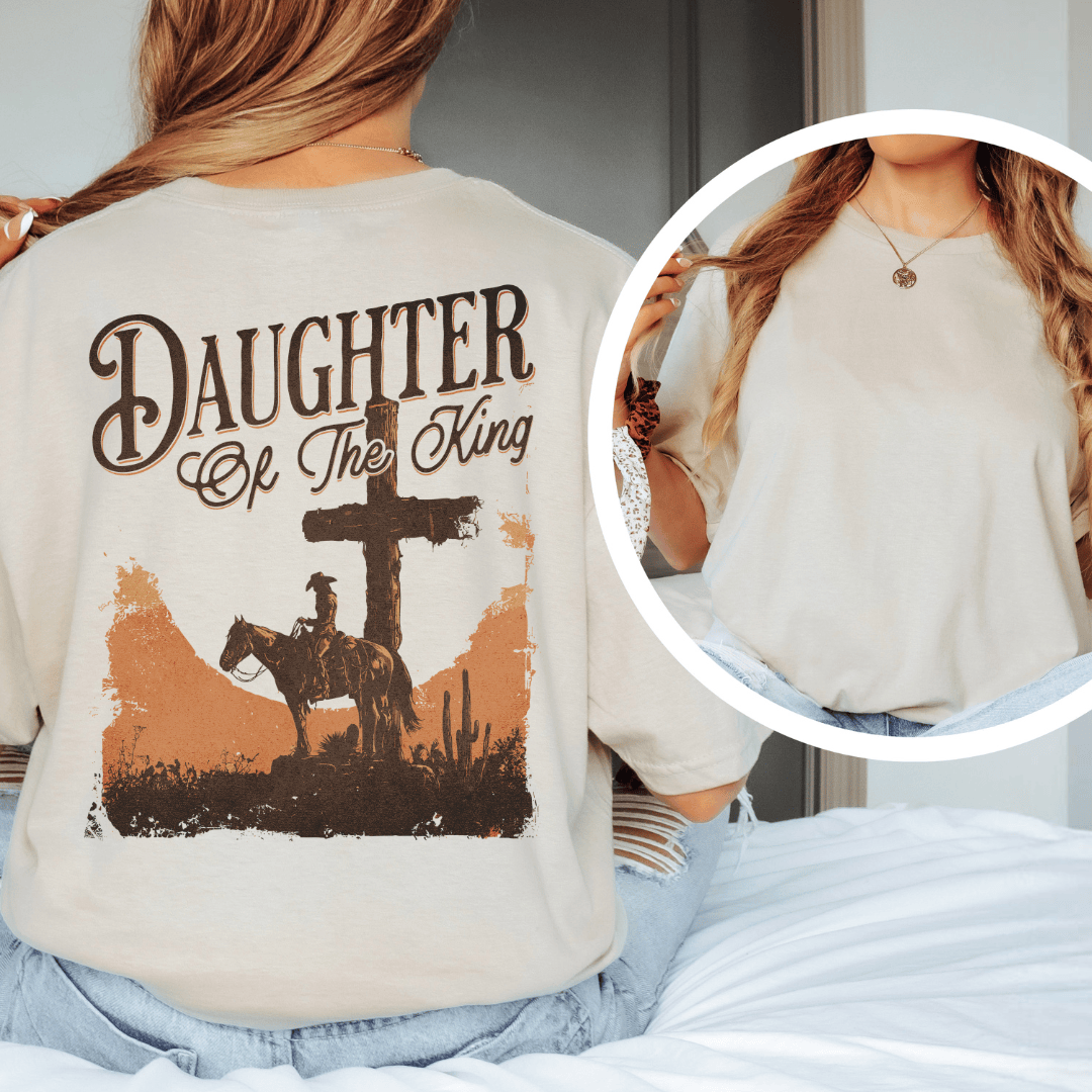 A woman wearing a graphic t-shirt with a western desert cross, cowboy on a horse, and Daughter of the King text.
