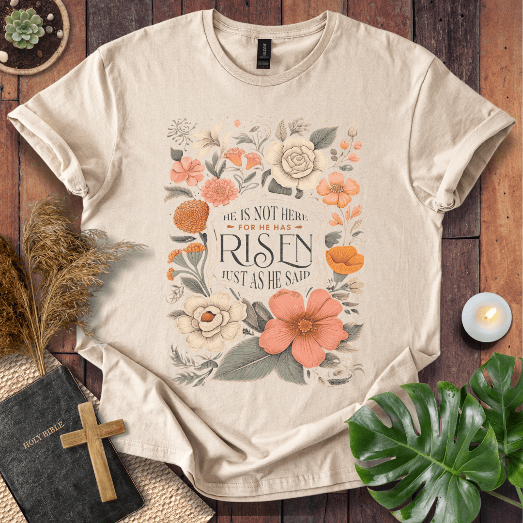 Christian Easter t-shirt with vintage flowers and He Is Risen Matthew 28:6 text on a rustic wood background.