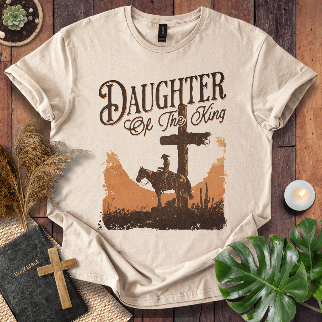 Western Christian t shirt for women featuring a rider on a horse by a cross in a desert sunset.