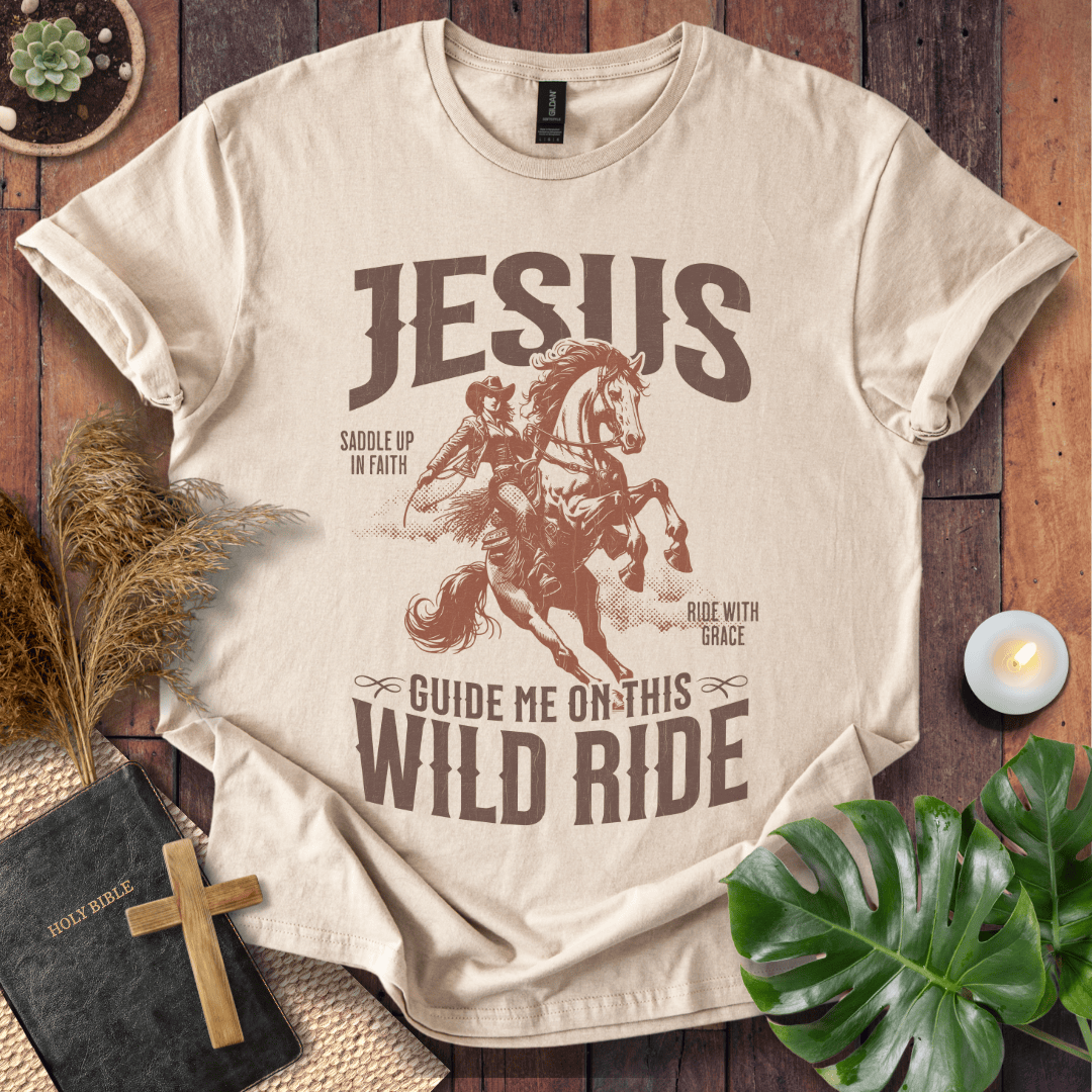 Beige t-shirt with graphic design and text on a wooden surface with decorative items.