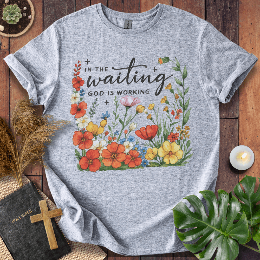 “In the Waiting God Is Working” Christian t-shirt with hand-lettered script and floral frame; encouragement faith tee.