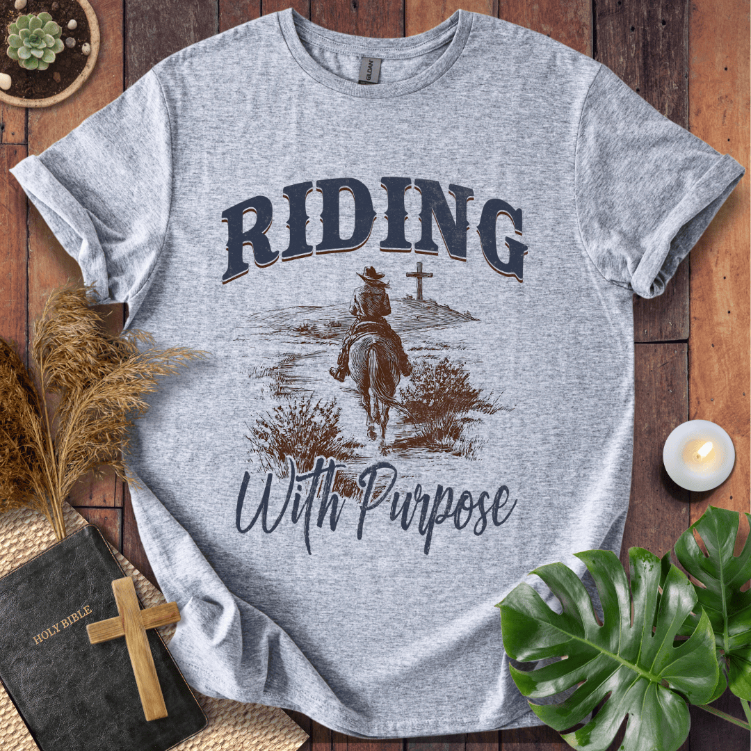 A lone rider on a horse approaching a cross on a Christian themed shirt with Riding With Purpose text.