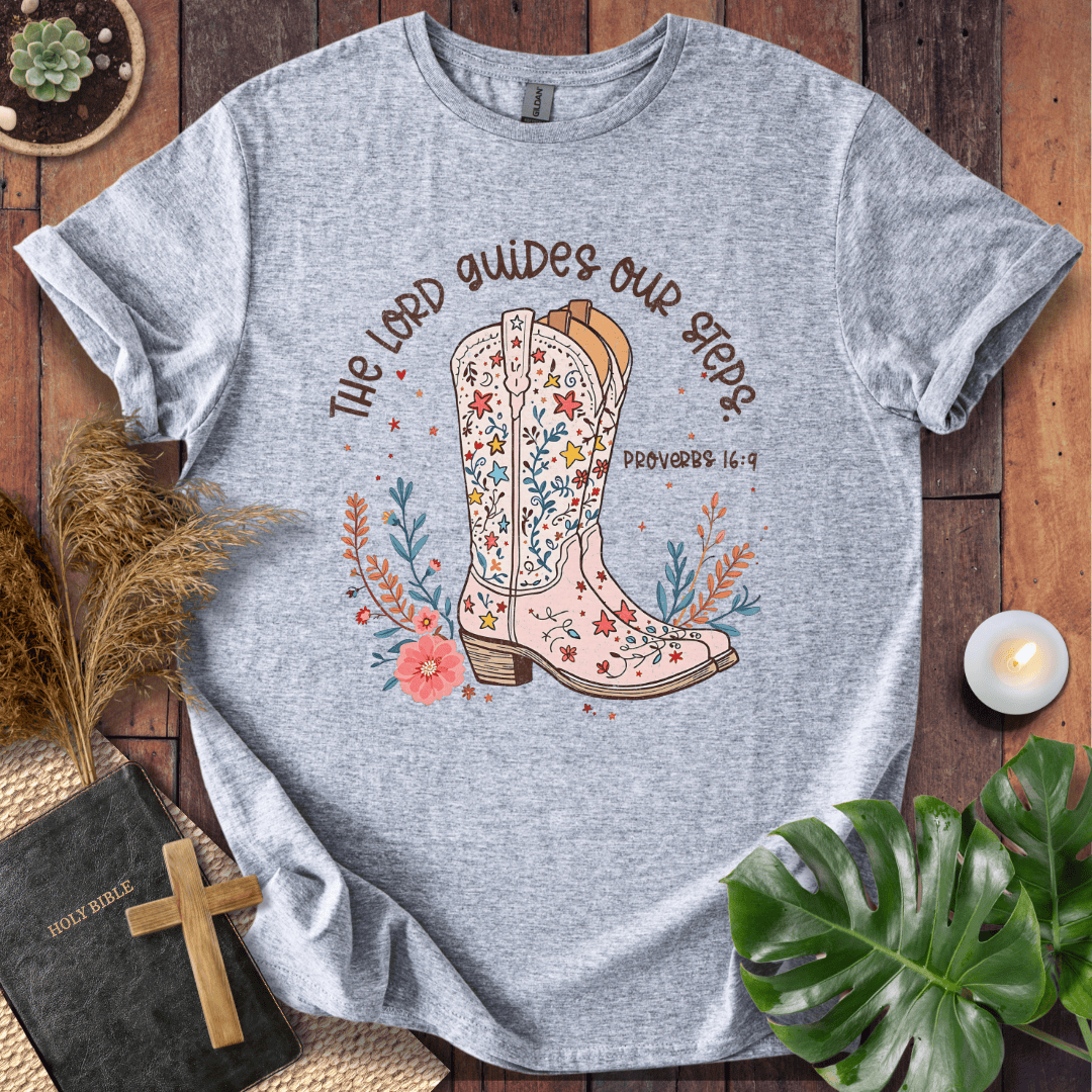 Christian t-shirt featuring a floral cowboy boot and the text The Lord Guides Our Steps Proverbs 16:9 in a rustic font.
