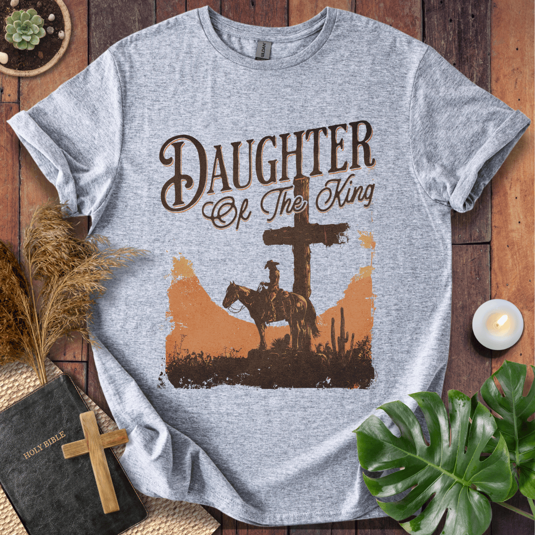 Western Christian t shirt for women featuring a rider on a horse by a cross in a desert sunset.