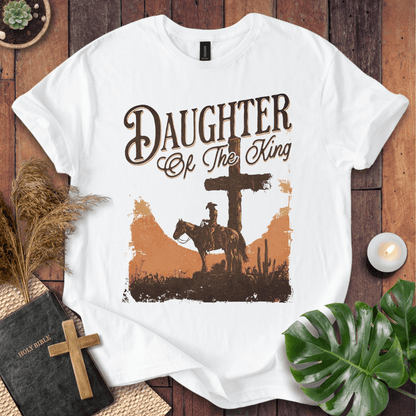 Western Christian t shirt for women featuring a rider on a horse by a cross in a desert sunset.