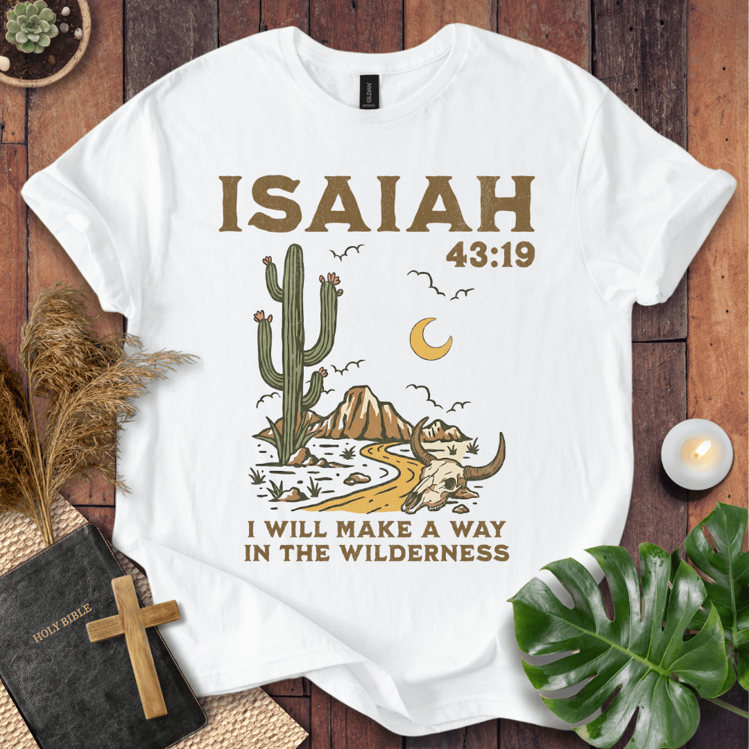 White t-shirt with cactus and skull design and 'Isaiah 43:19' text on a wooden surface.