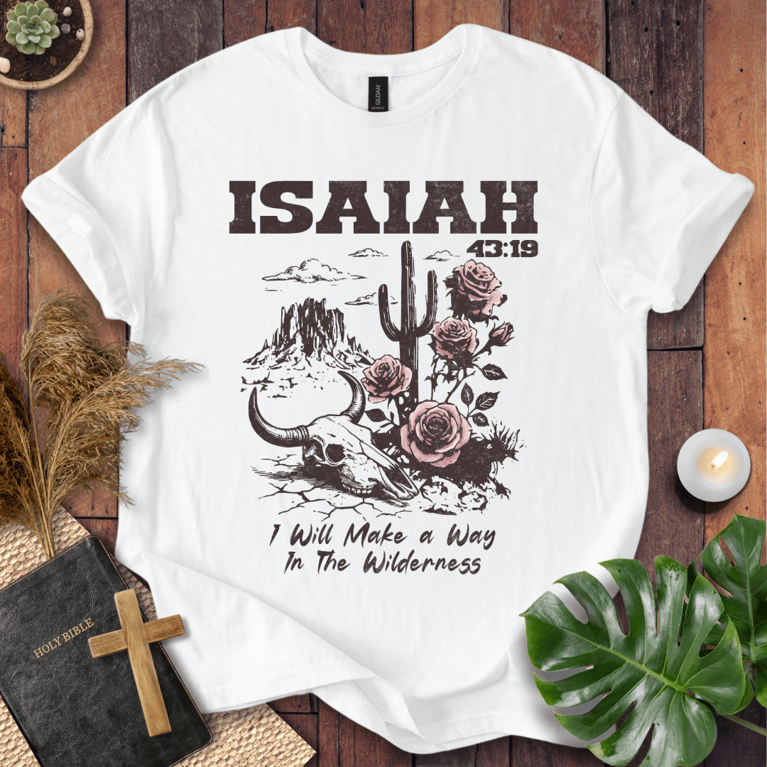 White t-shirt with 'ISAIAH 43:19' design on a wooden surface with decorative items.