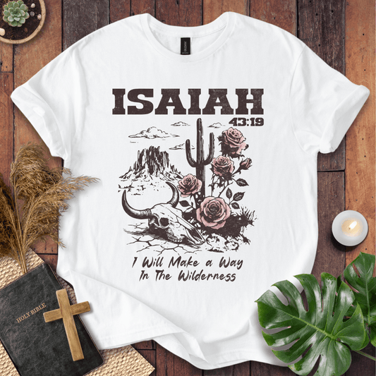 White t-shirt with 'ISAIAH 43:19' design on a wooden surface with decorative items.