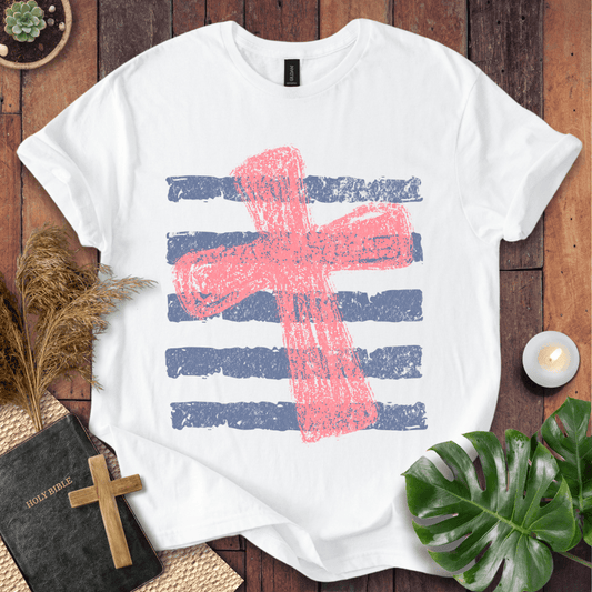Distressed pink cross over blue horizontal stripes on a t-shirt, styled with a Bible and wooden cross.