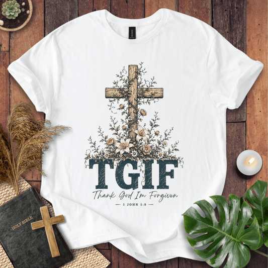 White t-shirt with 'Jesus Paid My Ransom' design on a wooden surface with decorative items.