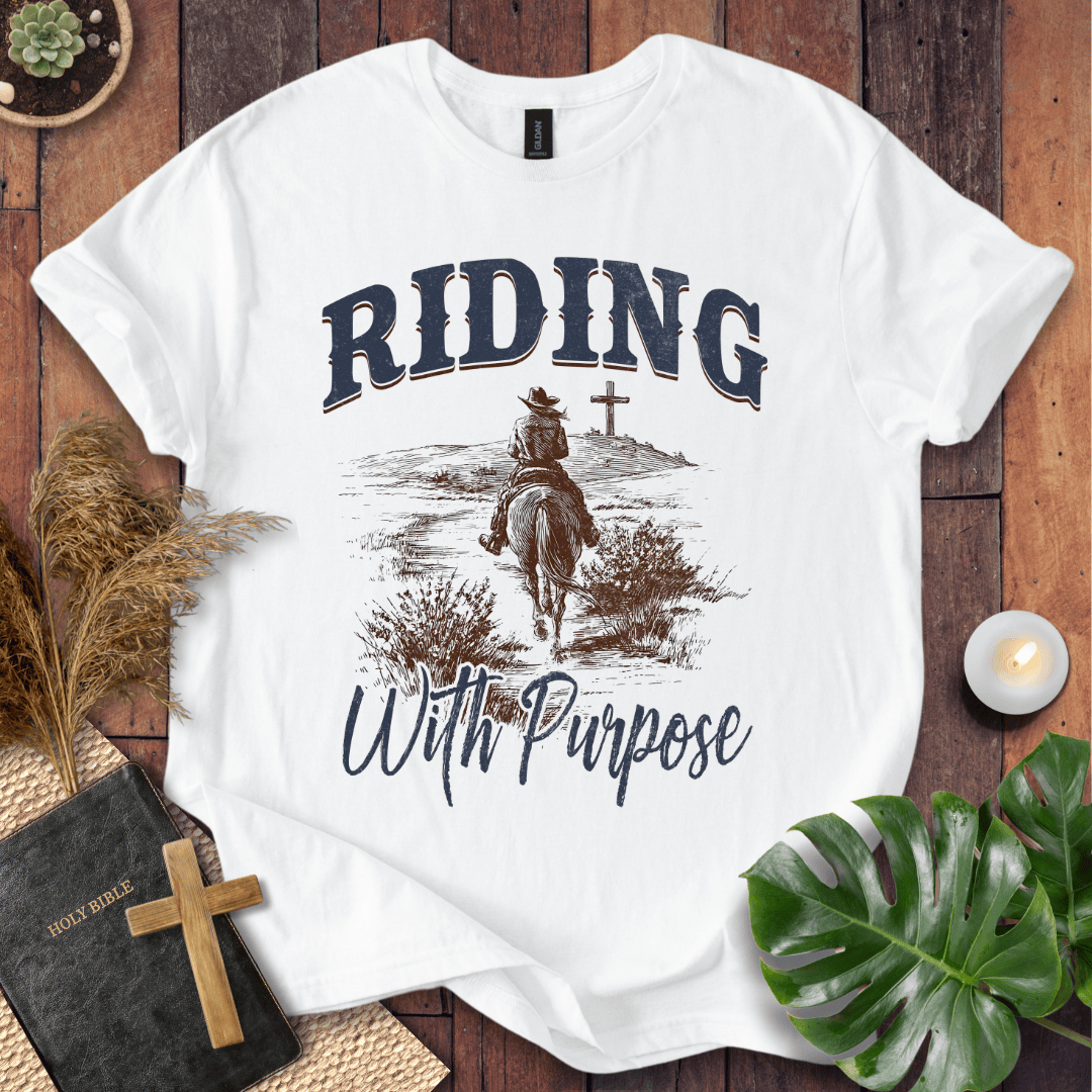 A lone rider on a horse approaching a cross on a Christian themed shirt with Riding With Purpose text.