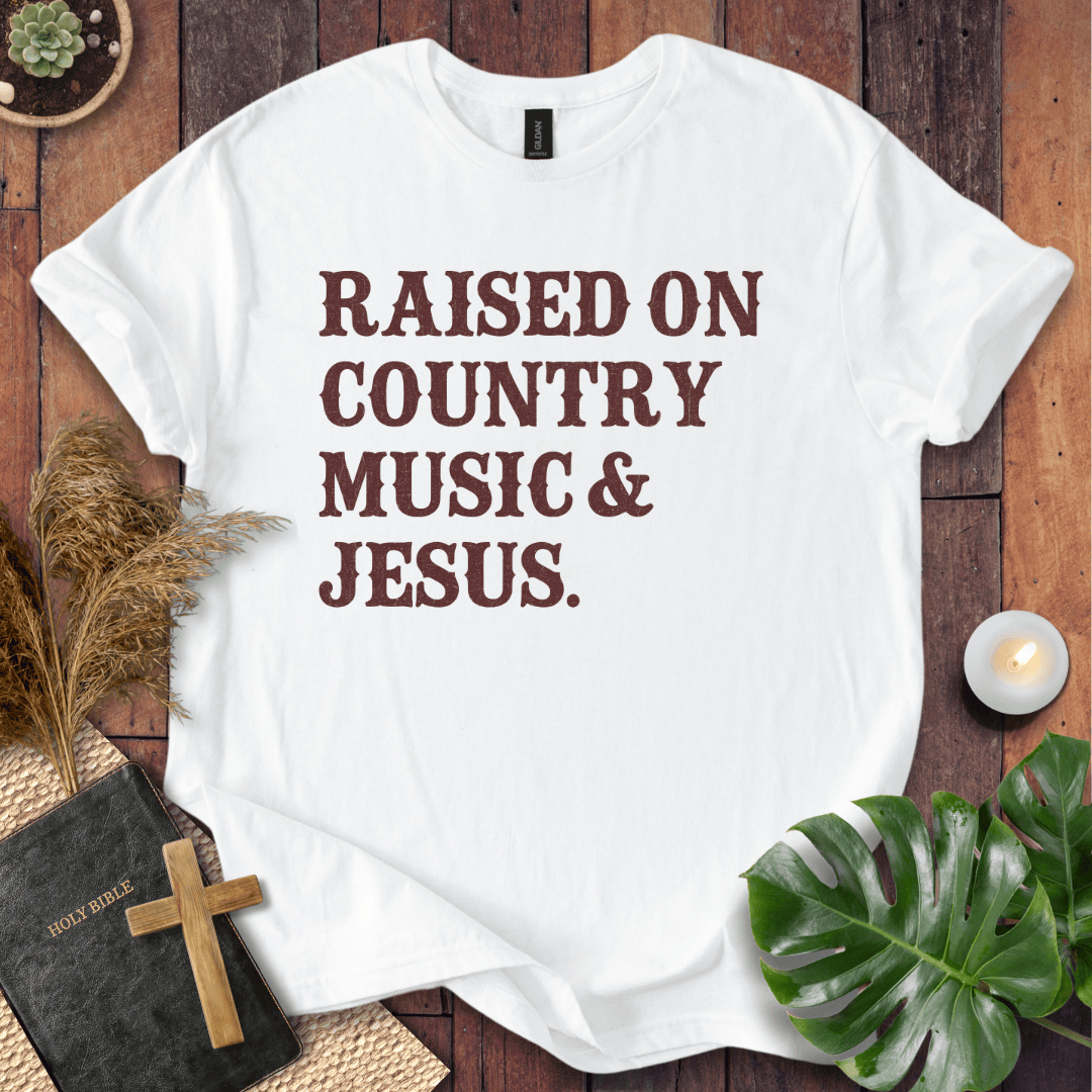 Christian t shirts for women with "Raised on Country Music & Jesus" in brown text on a rustic wood background.