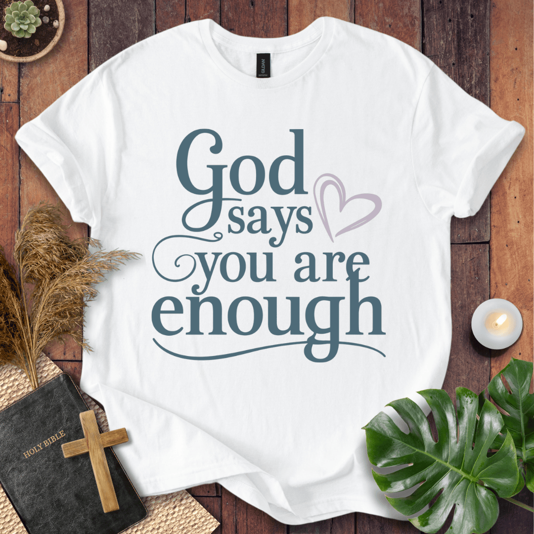 "God says you are enough" printed in teal on Christian t-shirt for women, styled with a Bible and wooden cross.