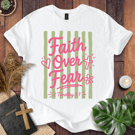 White t-shirt with 'Jesus Paid My Ransom' design on a wooden surface with decorative items.
