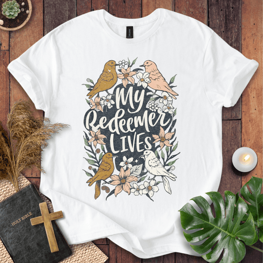 Christian Easter t-shirt with My Redeemer Lives text and birds on a wooden table next to a Holy Bible and a wooden cross.