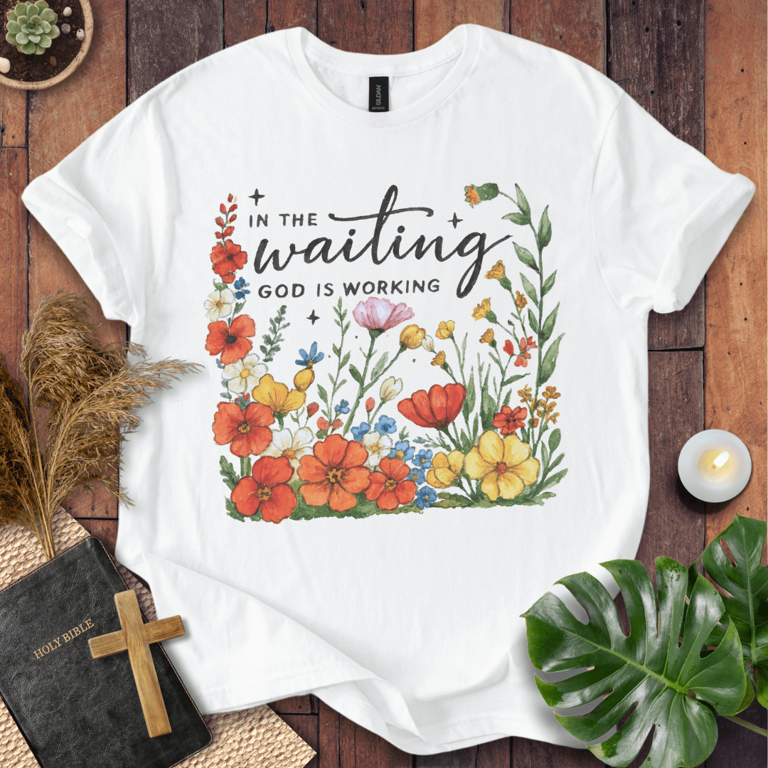 “In the Waiting God Is Working” Christian t-shirt with hand-lettered script and floral frame; encouragement faith tee.